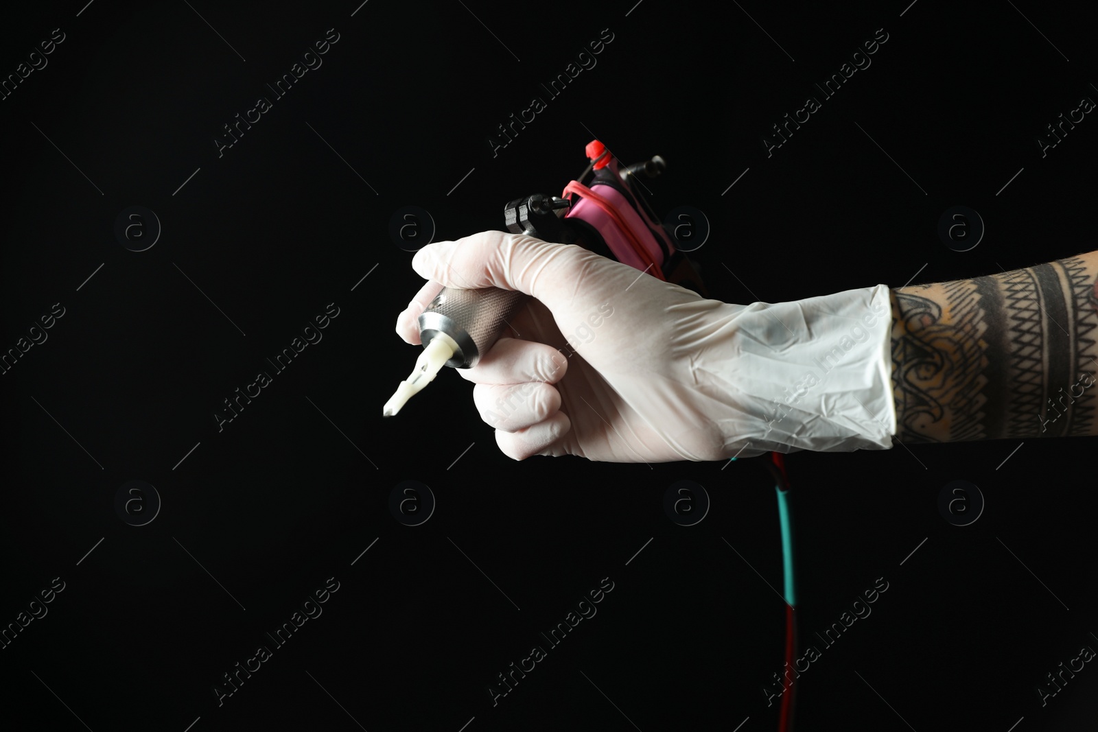 Photo of Tattoo artist with professional machine on black background, closeup