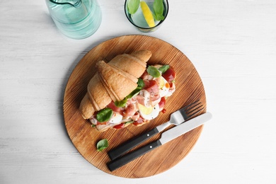Photo of Tasty croissant sandwich with bacon on wooden background, top view