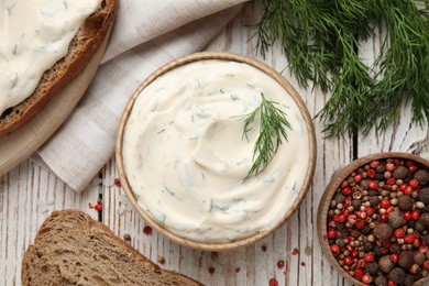 Photo of Tasty creamy dill sauce, bread and ingredients on white wooden table, flat lay