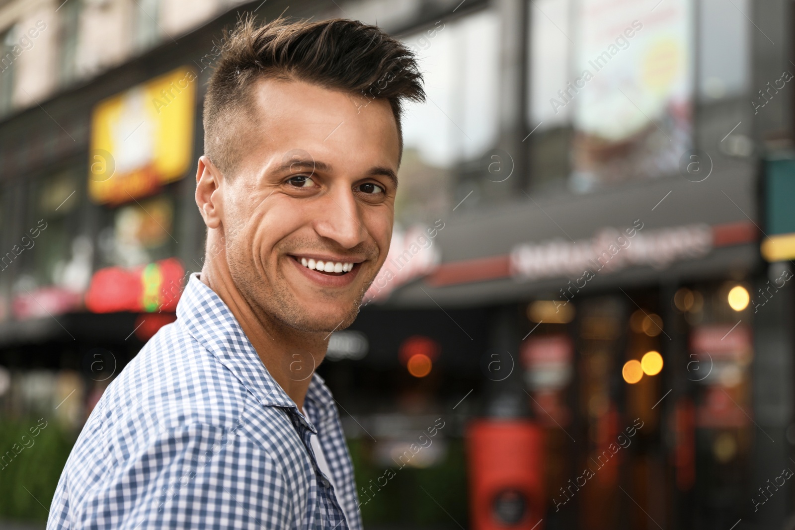 Photo of Portrait of handsome young man on city street. Space for text