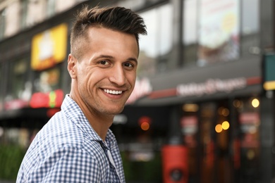 Portrait of handsome young man on city street. Space for text