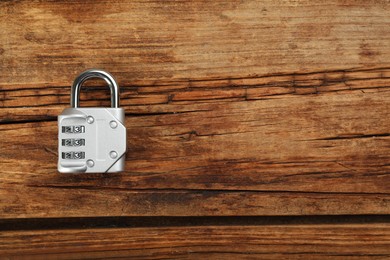 Photo of Modern combination lock on wooden table, top view. Space for text