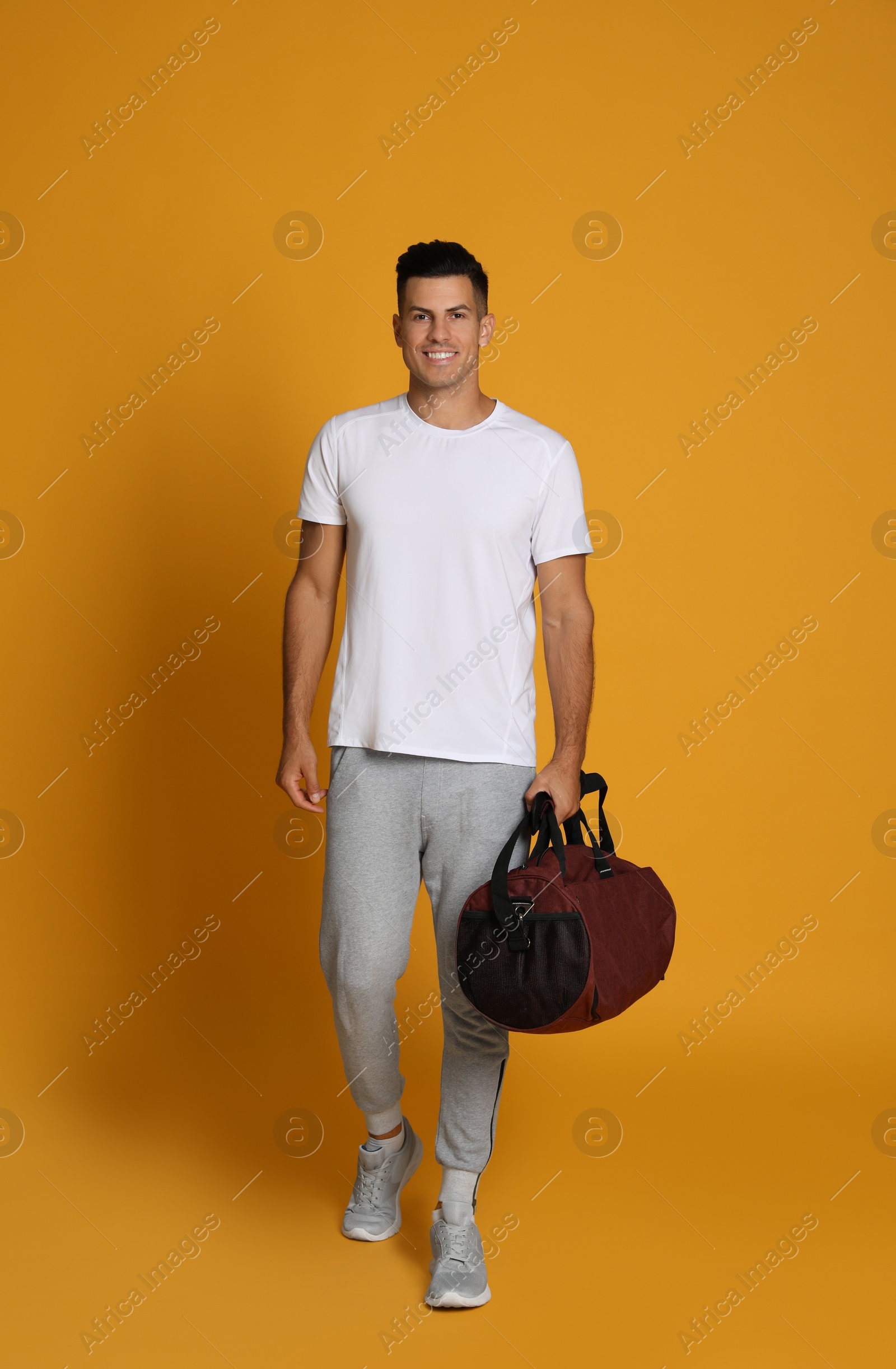 Photo of Handsome man with sports bag on yellow background