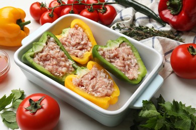 Photo of Raw stuffed peppers and ingredients on white table