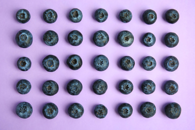 Fresh ripe blueberries on lilac background, flat lay