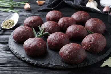 Photo of Many fresh raw meatballs on black wooden table, closeup
