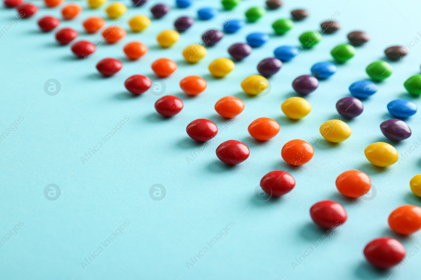 Photo of Different delicious glazed candies on light blue background, closeup. Space for text