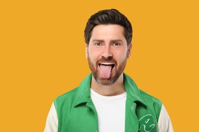 Man showing his tongue on orange background