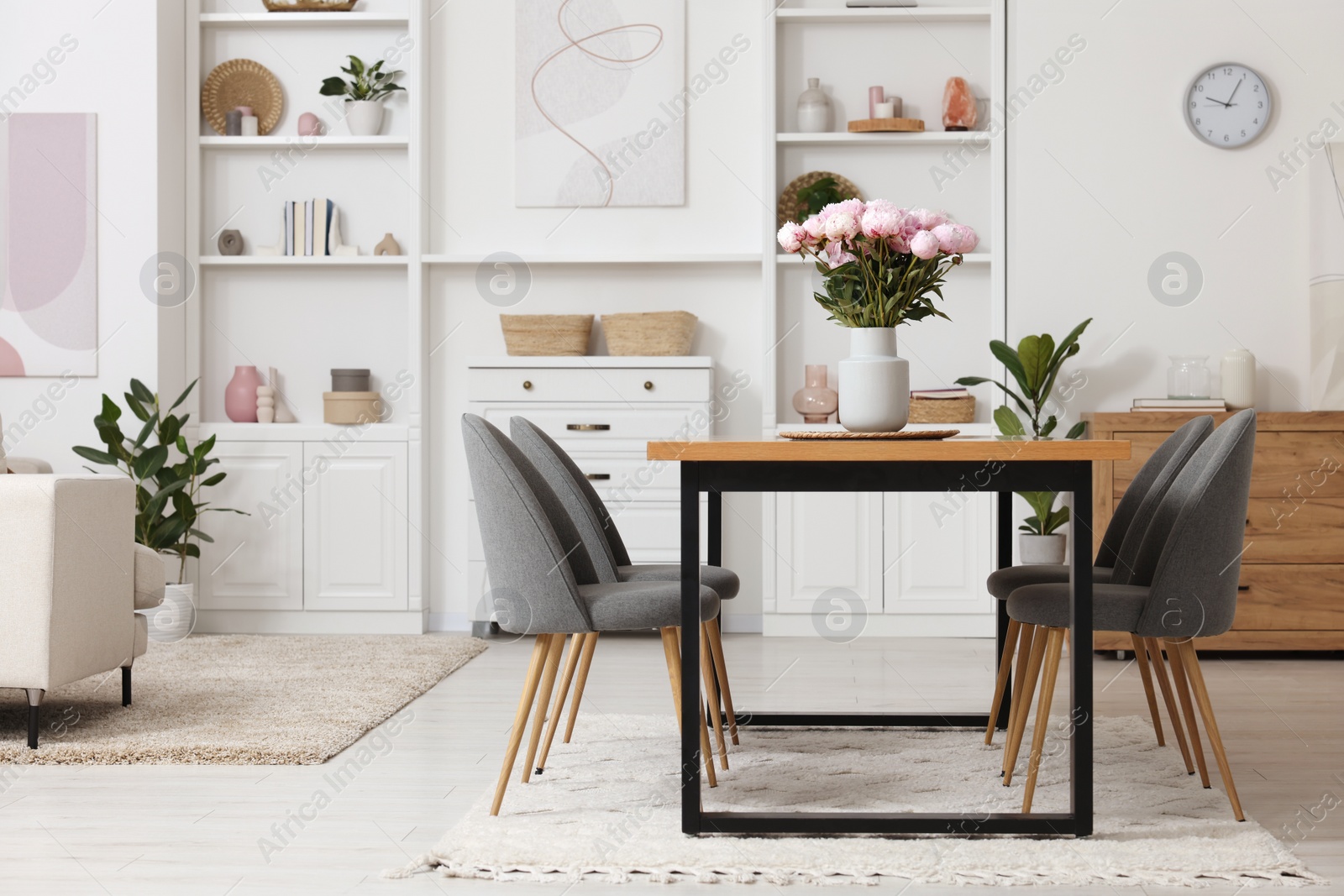 Photo of Stylish dining room with cosy furniture and flowers