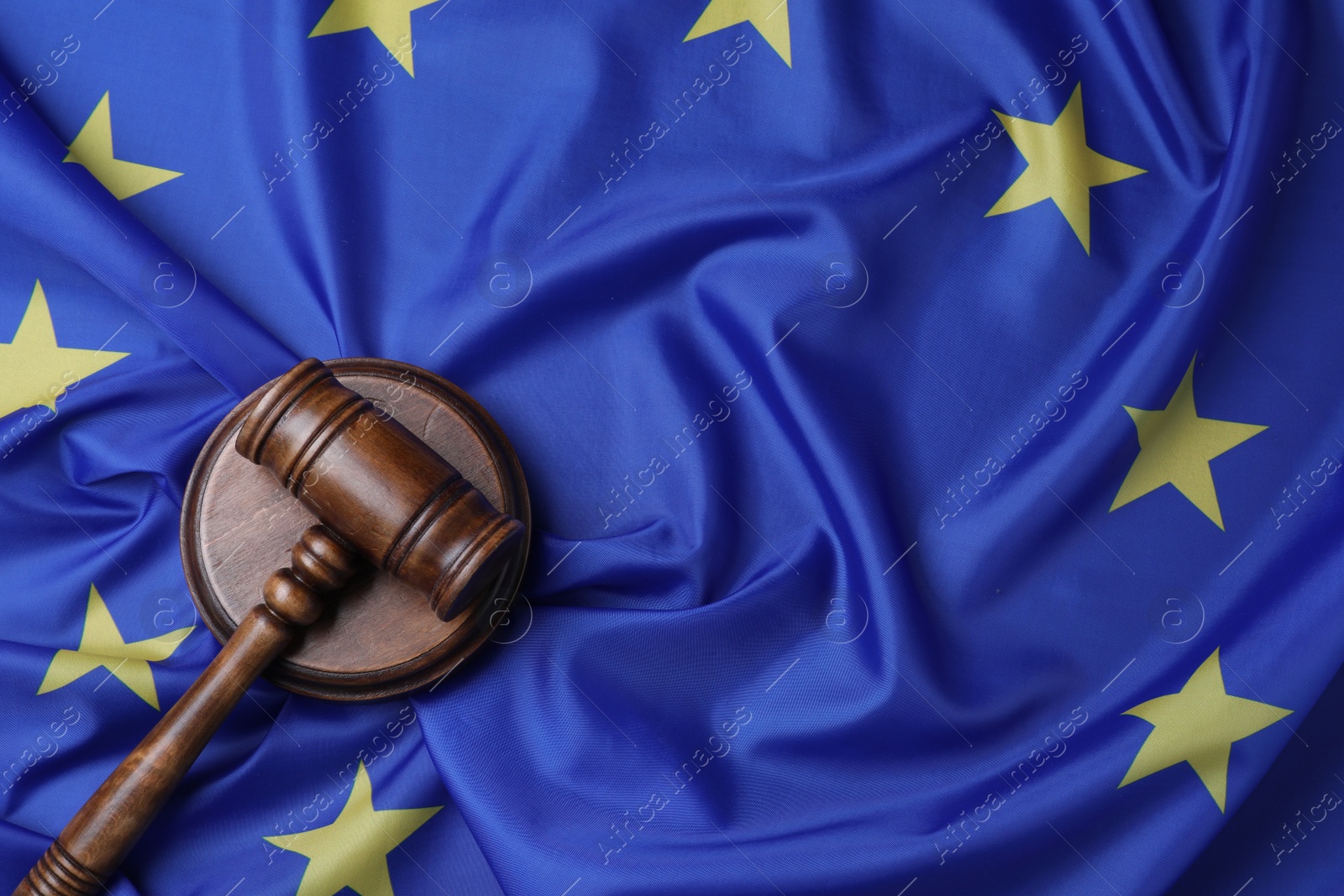 Photo of Wooden judge's gavel on flag of European Union, top view. Space for text