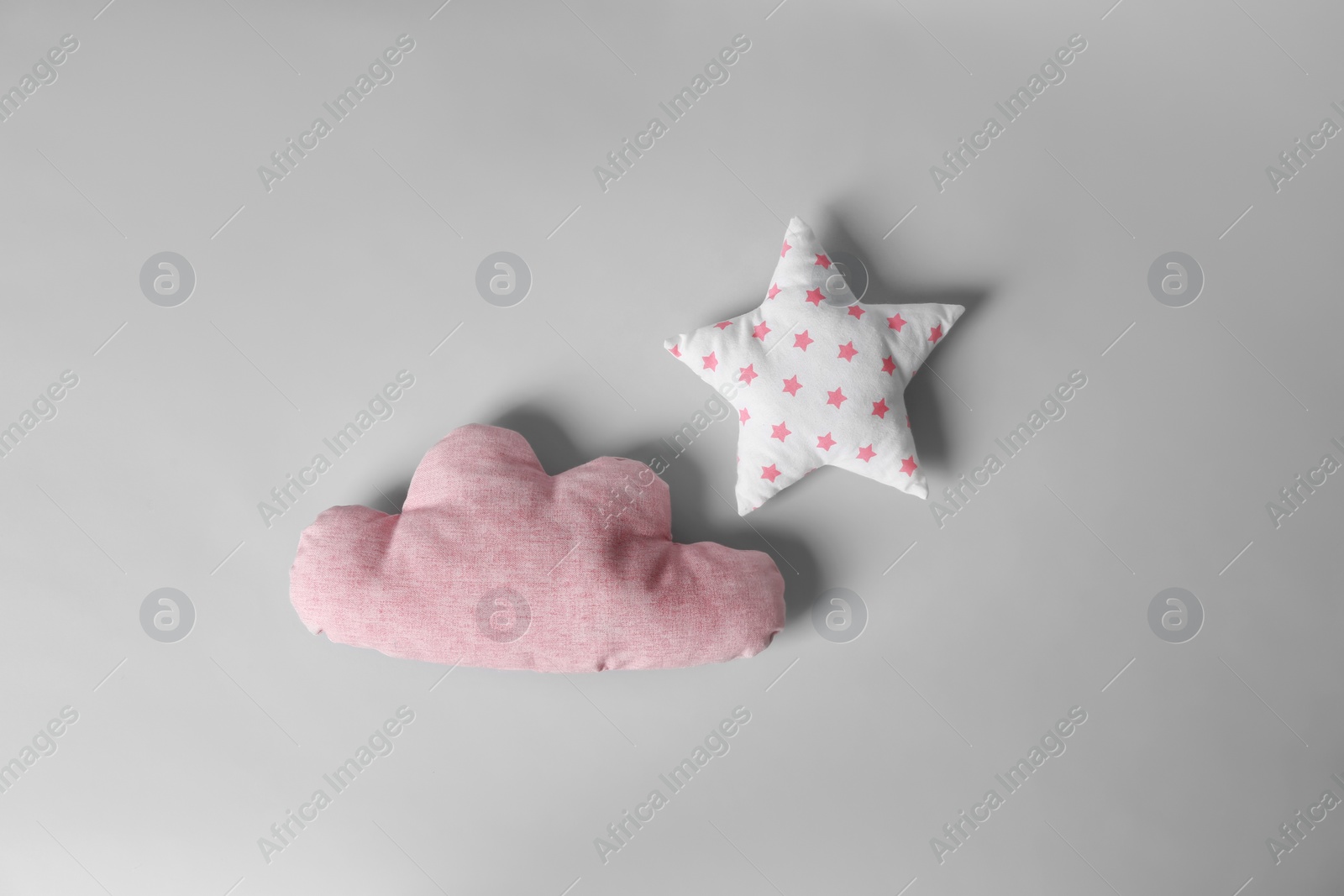 Photo of Soft decorative pillows in shape of cloud and star on light background