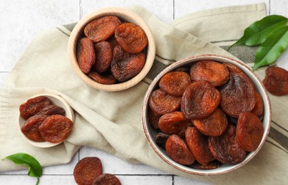 Photo of Tasty apricots with leaves on white tiled table, flat lay. Dried fruits