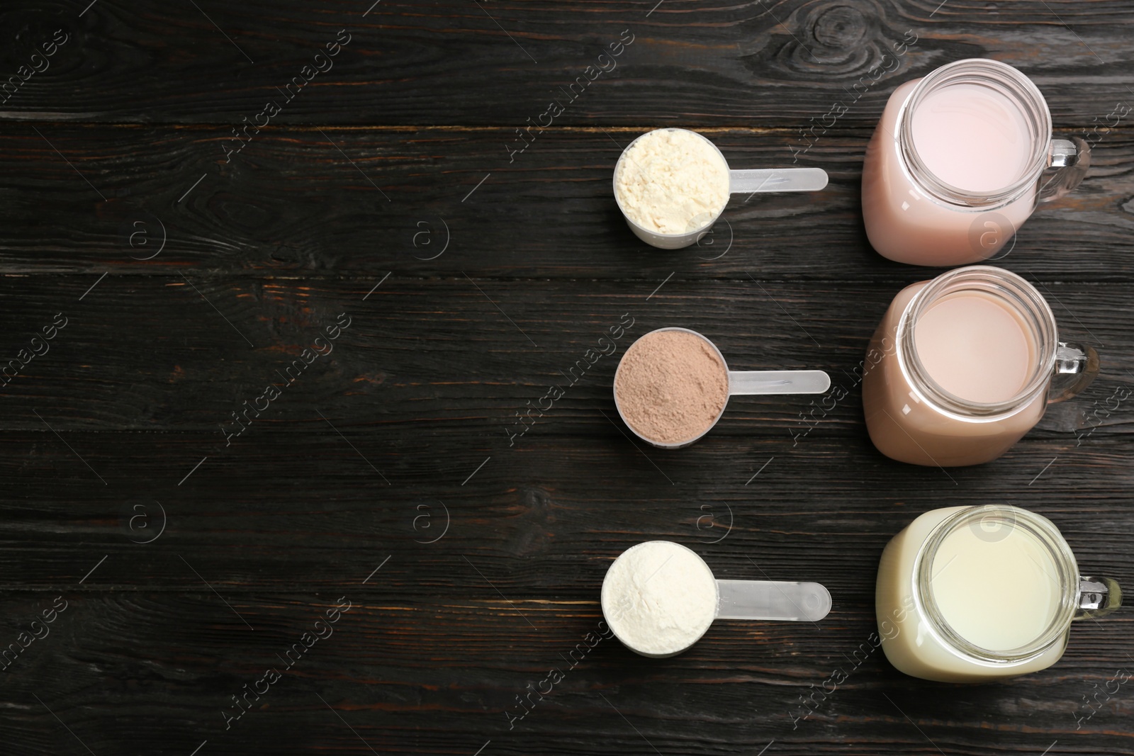 Photo of Protein shakes and powder on black wooden table, flat lay. Space for text