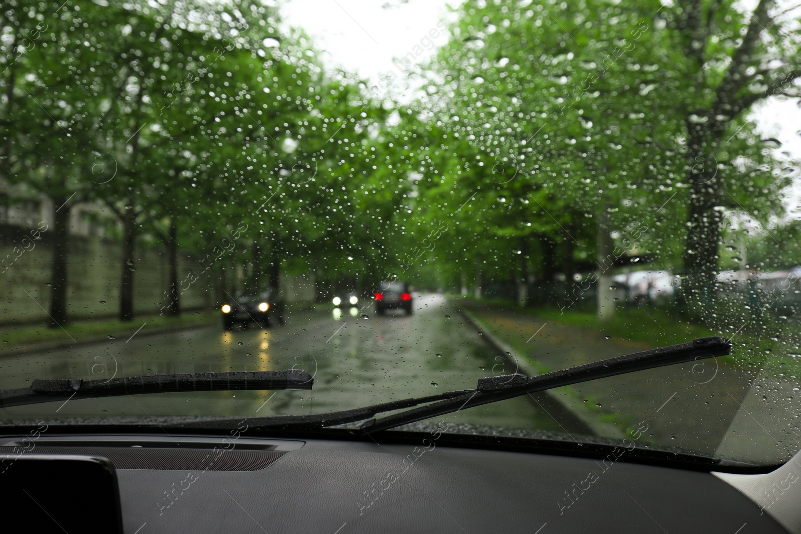 Photo of Blurred view of road through wet car window. Rainy weather