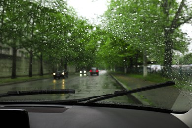 Photo of Blurred view of road through wet car window. Rainy weather