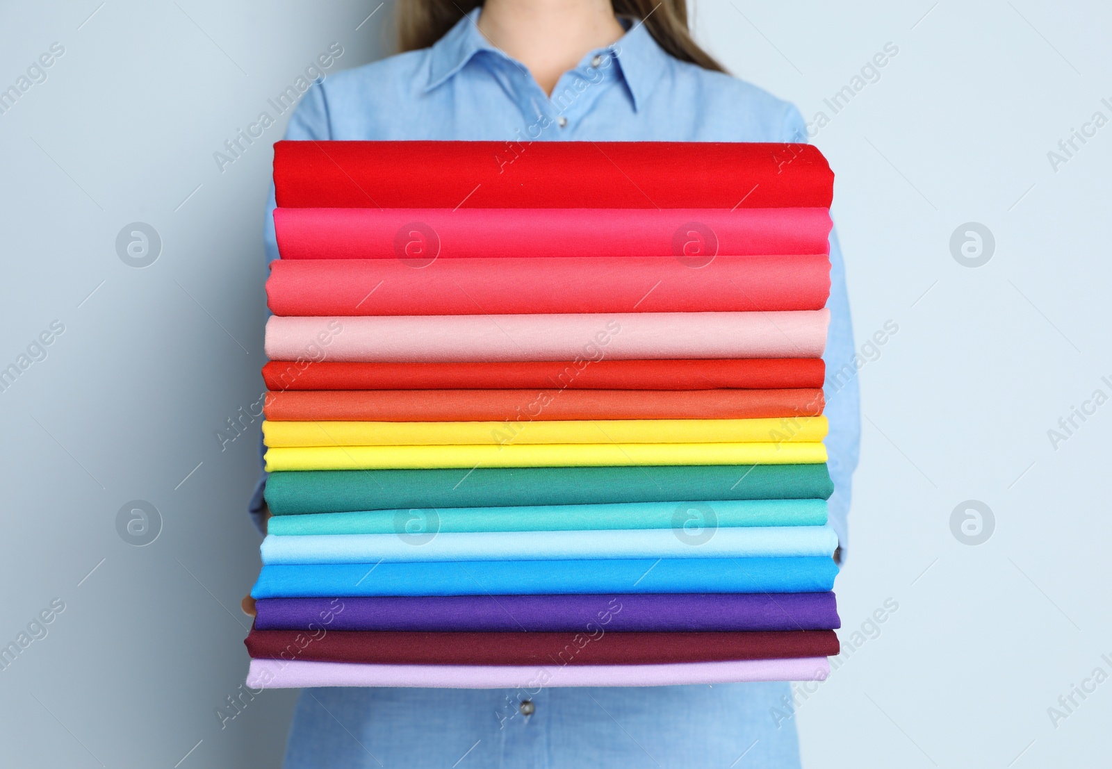 Photo of Woman holding pile of colorful t-shirts, closeup