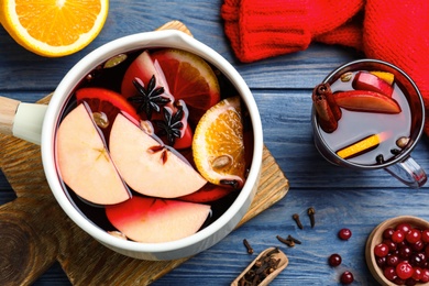 Delicious mulled wine and ingredients on blue wooden table, flat lay