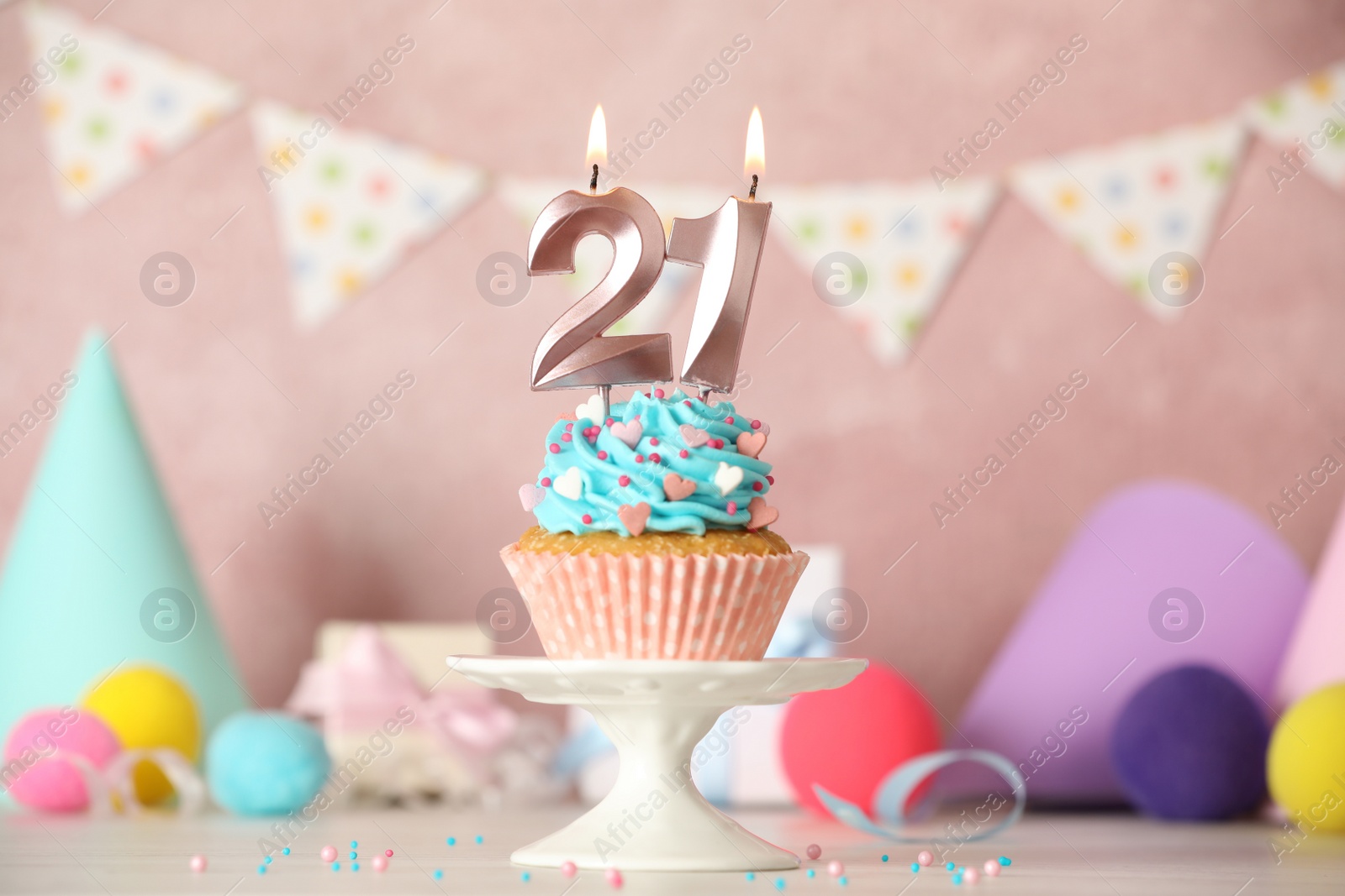 Photo of 21th birthday. Delicious cupcake with number shaped candles for coming of age party on white table