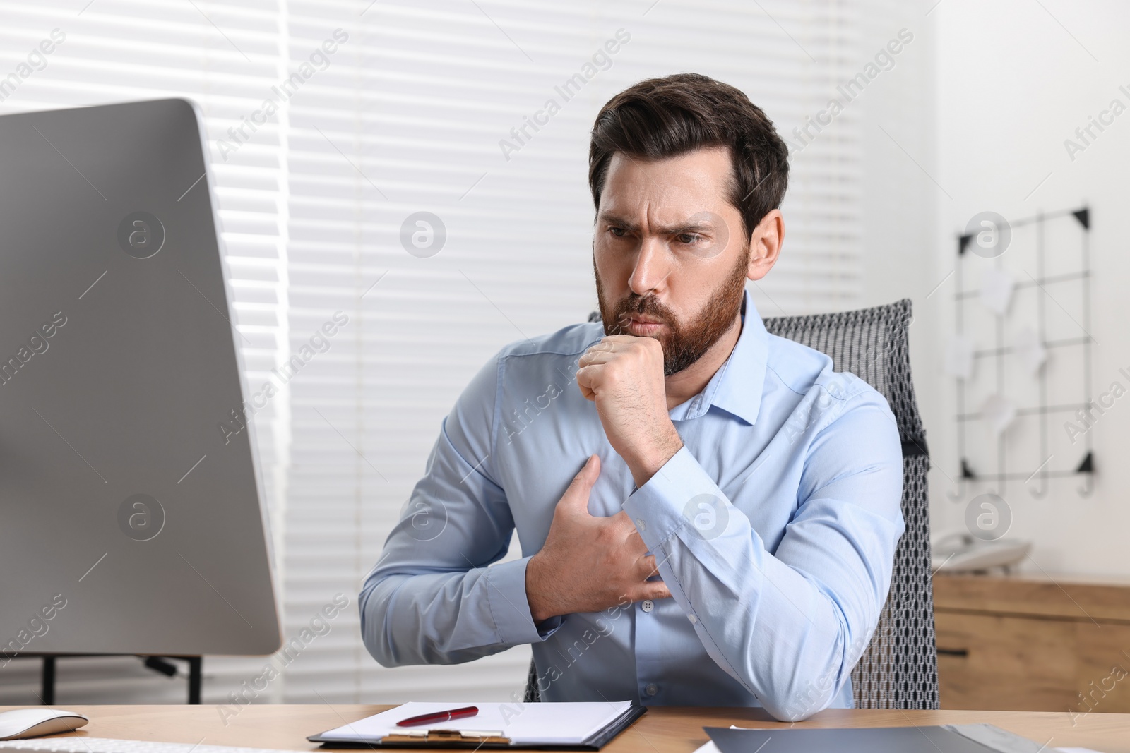 Photo of Sick man coughing at workplace in office. Cold symptoms