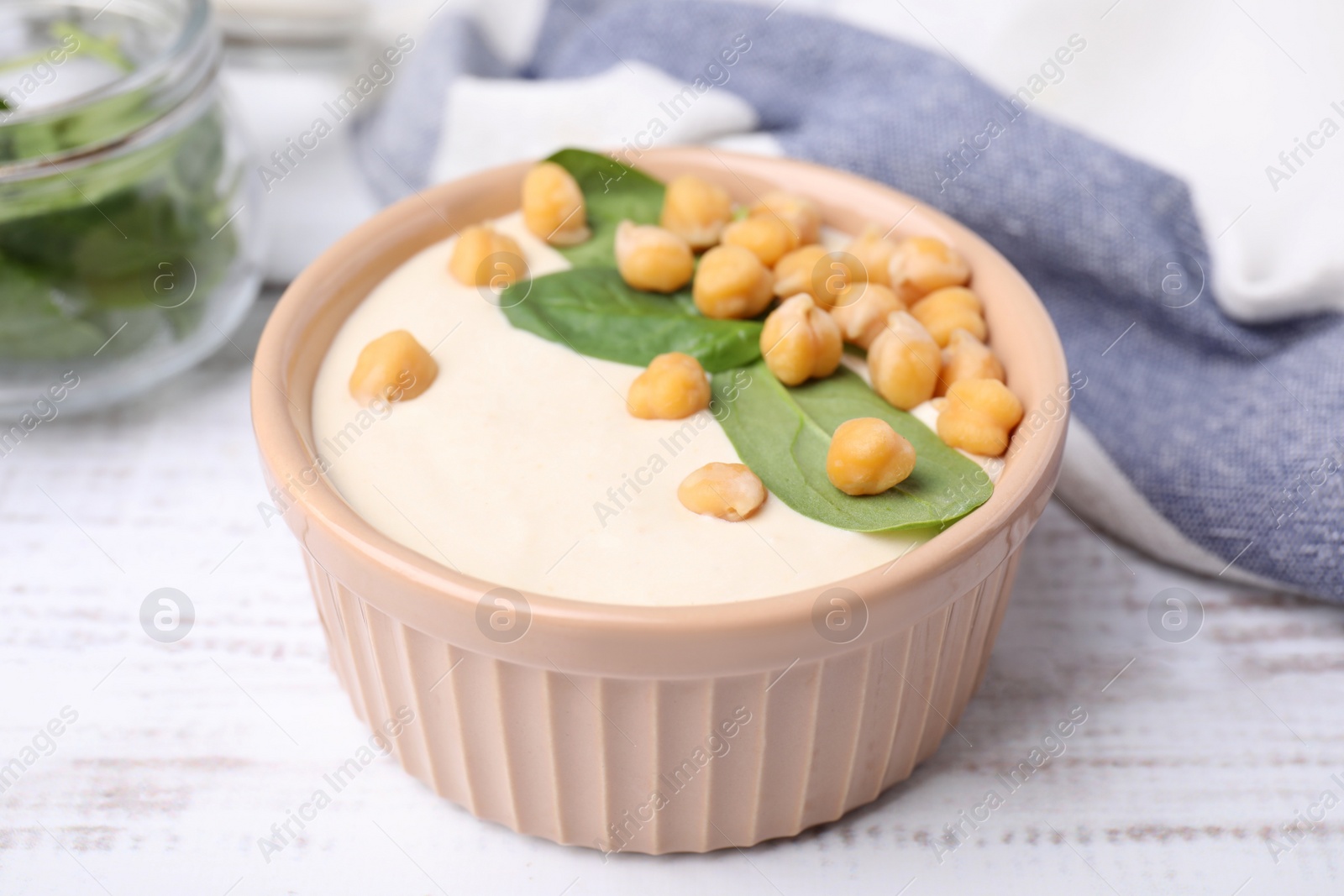 Photo of Tasty chickpea soup in bowl on white wooden table, closeup