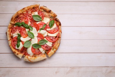 Photo of Delicious Caprese pizza with tomatoes, mozzarella and basil on light wooden table, top view. Space for text