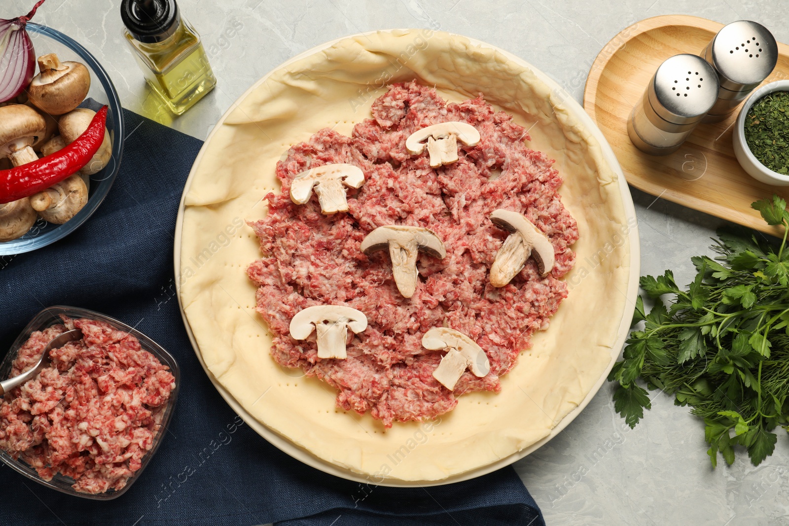 Photo of Flat lay composition with raw dough and ingredients on light grey table. Baking meat pie