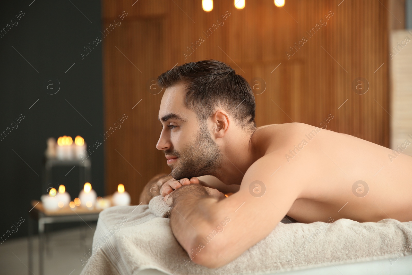 Photo of Handsome man relaxing on massage table in spa salon