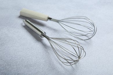 Photo of Metal whisks on gray table, closeup. Kitchen tool