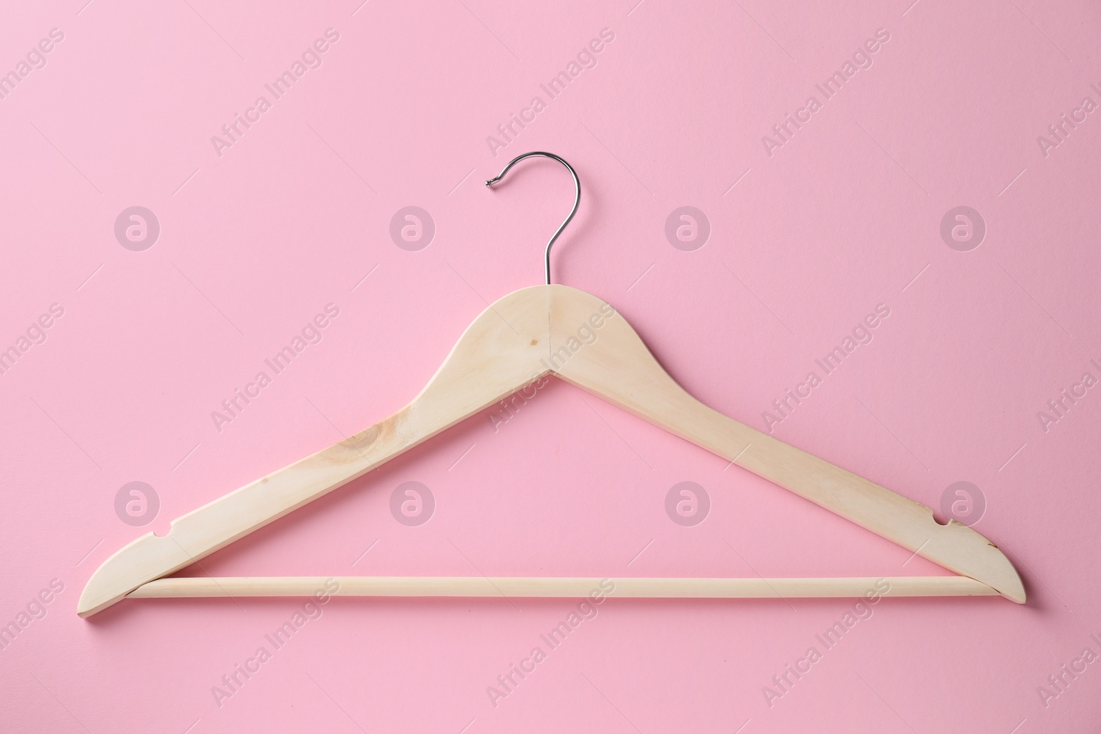 Photo of One wooden hanger on pink background, top view