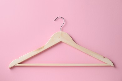 Photo of One wooden hanger on pink background, top view