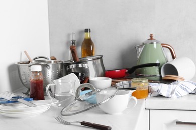 Many dirty utensils, cookware and dishware on countertop in messy kitchen