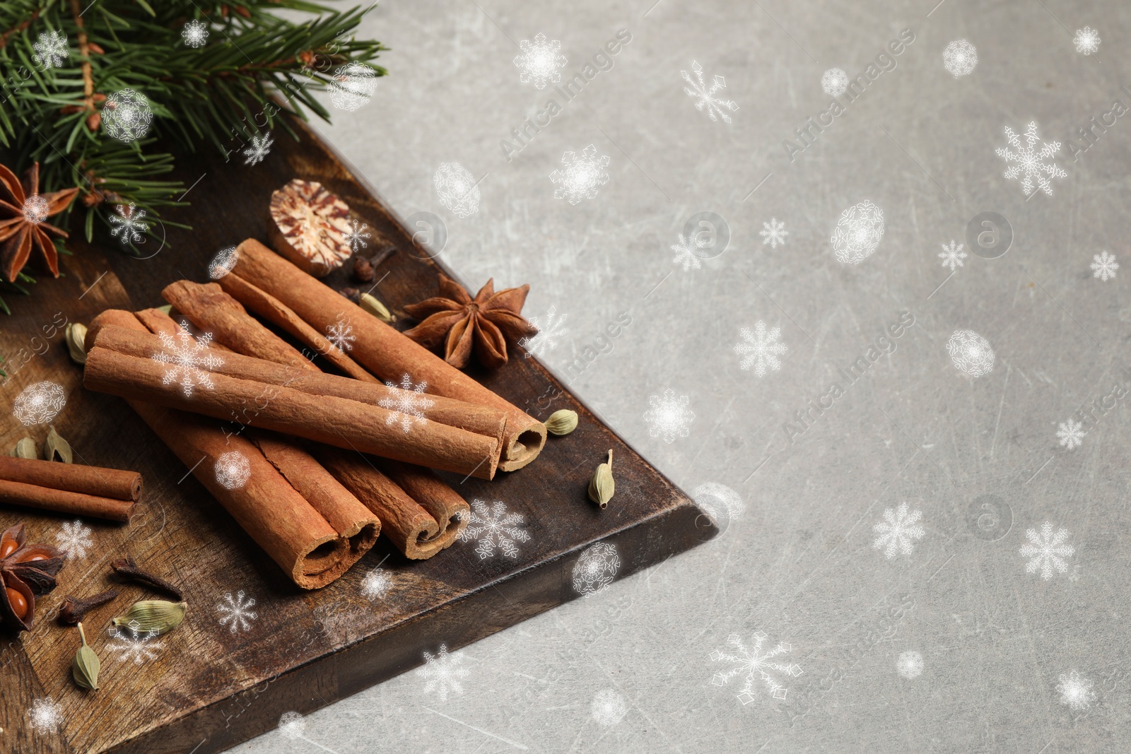 Image of Different spices and fir tree branches on grey table, space for text. Cinnamon, anise, cardamom, cloves, nutmeg