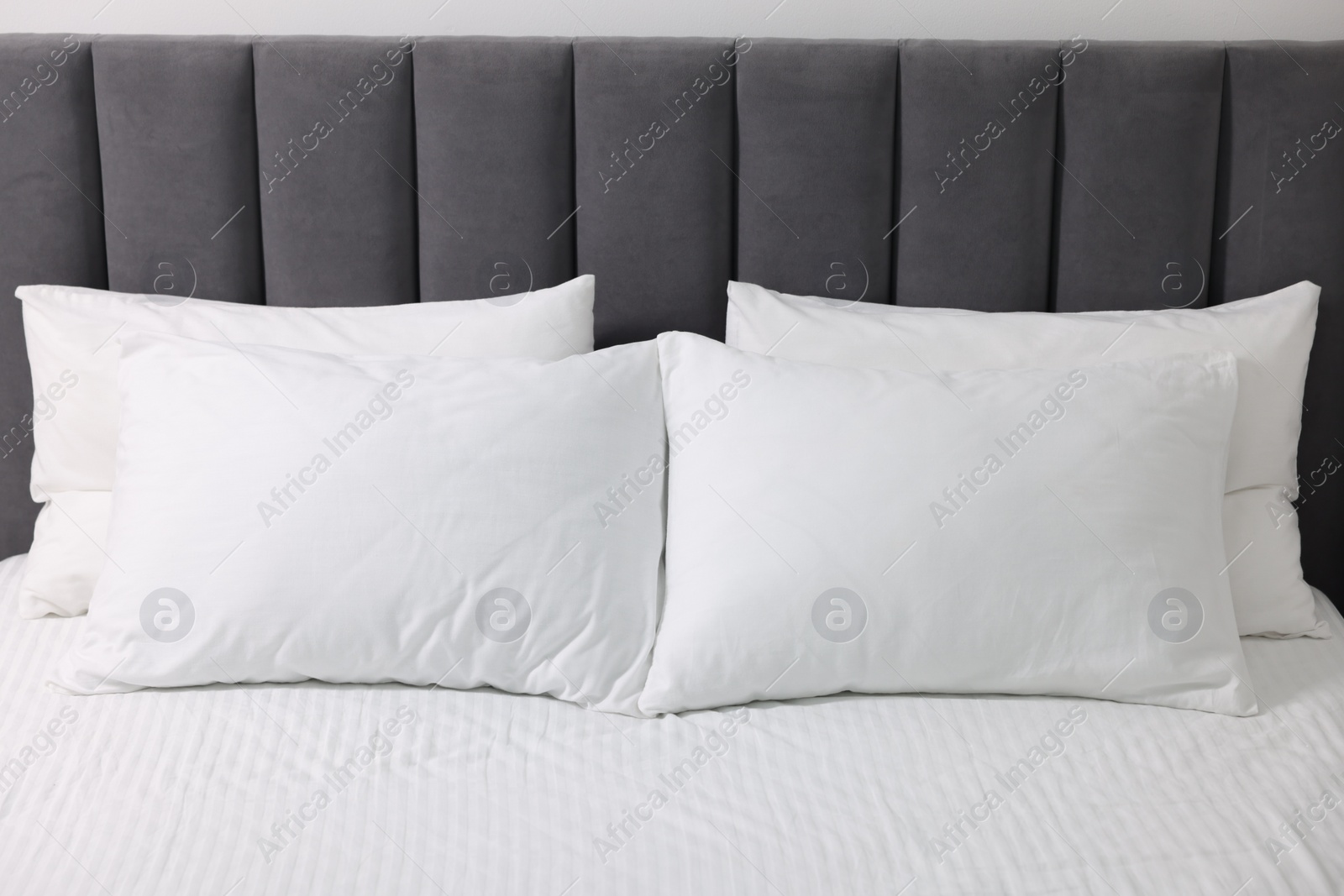 Photo of Soft white pillows and bedsheet on bed