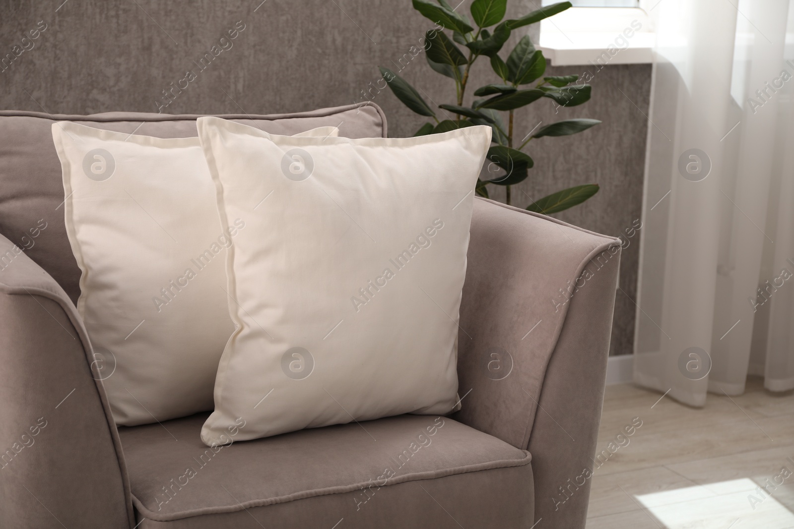 Photo of Soft pillows on armchair in living room