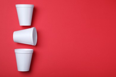 Photo of White styrofoam cups on red background, flat lay. Space for text
