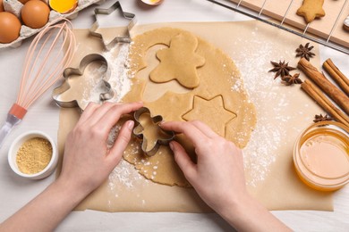 Photo of Woman making Christmas cookies with cutters at white wooden table, top view