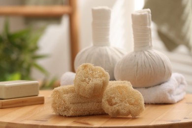 Loofah sponges, soap and herbal bags on wooden table indoors, closeup