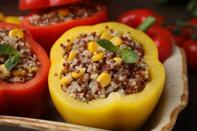 Photo of Quinoa stuffed bell peppers and basil in baking dish, closeup