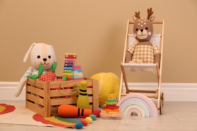Set of different cute toys on floor near beige wall
