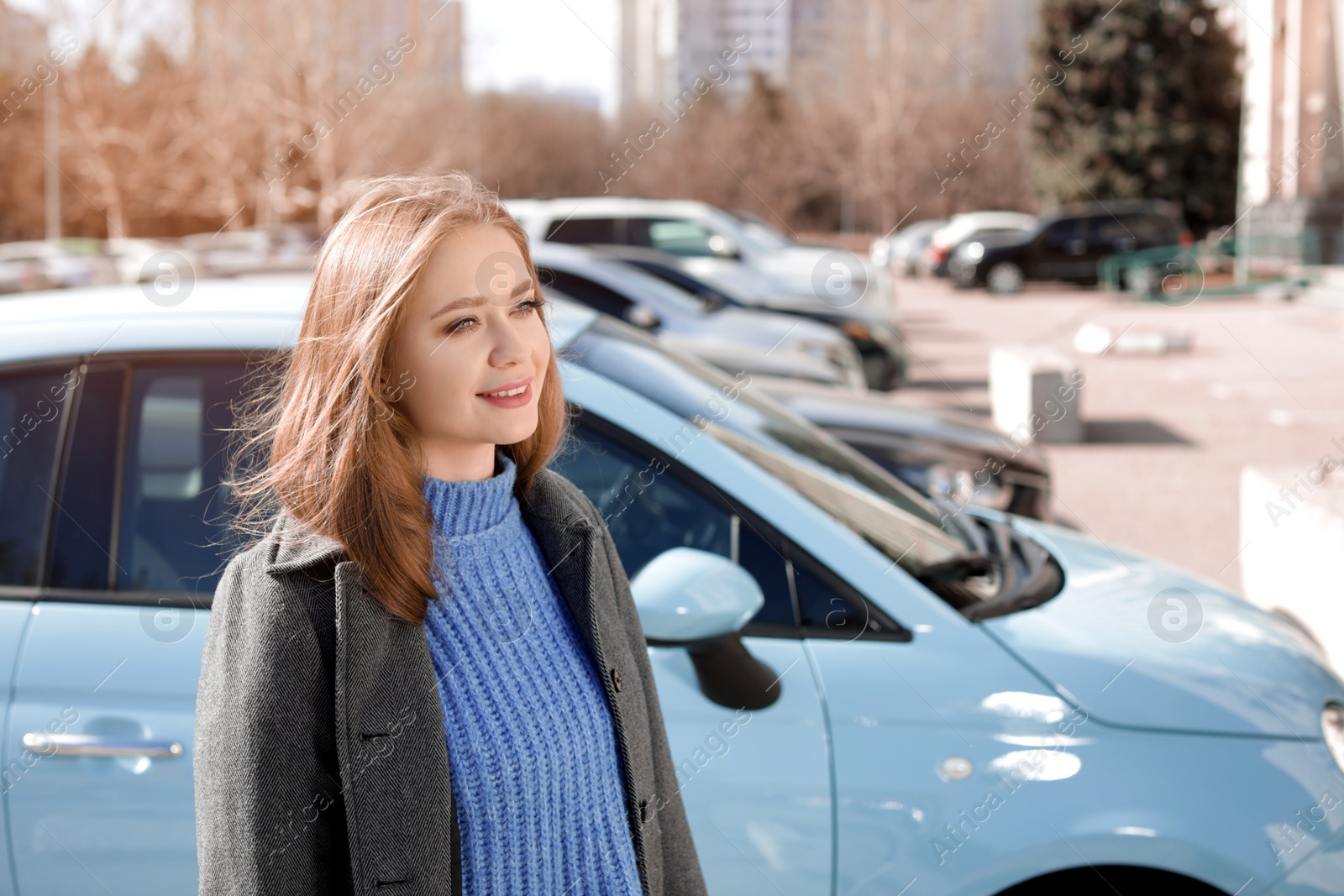 Photo of Portrait of beautiful young woman near parked cars on sunny day