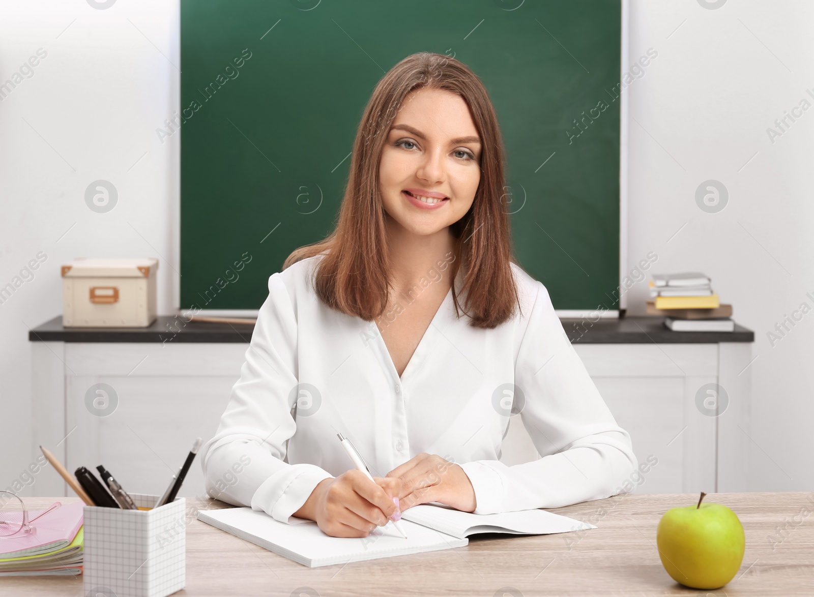 Photo of Portrait of female teacher sitting at table in classroom