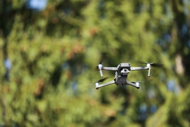 Photo of Modern drone flying outdoors on sunny day, space for text