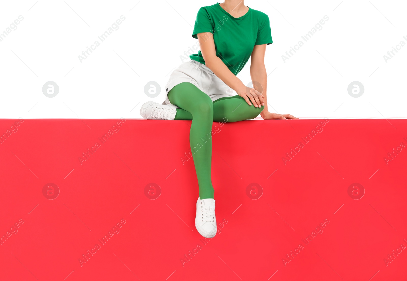 Photo of Woman wearing green tights sitting on color background, closeup