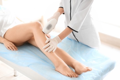 Photo of Woman undergoing hair removal procedure with photo epilator in salon