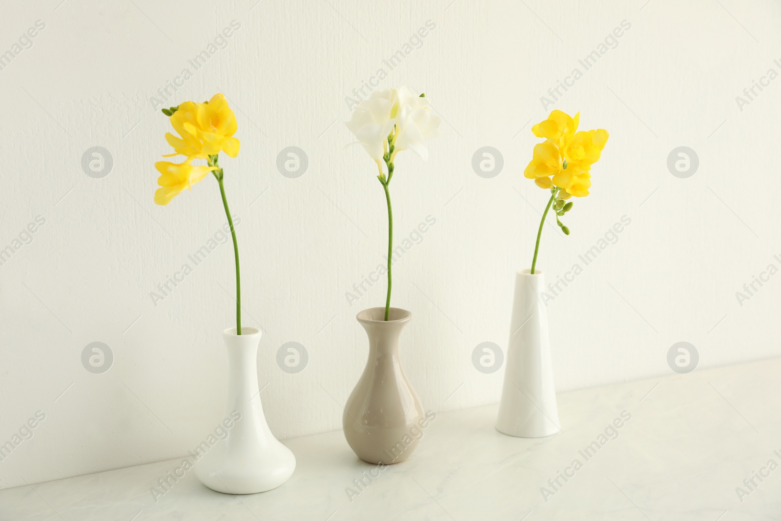 Photo of Beautiful freesia flowers on white marble table