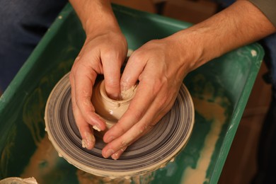 Photo of Clay crafting. Man making bowl on potter's wheel, closeup
