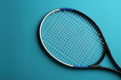 Tennis racket on blue background, top view. Sports equipment