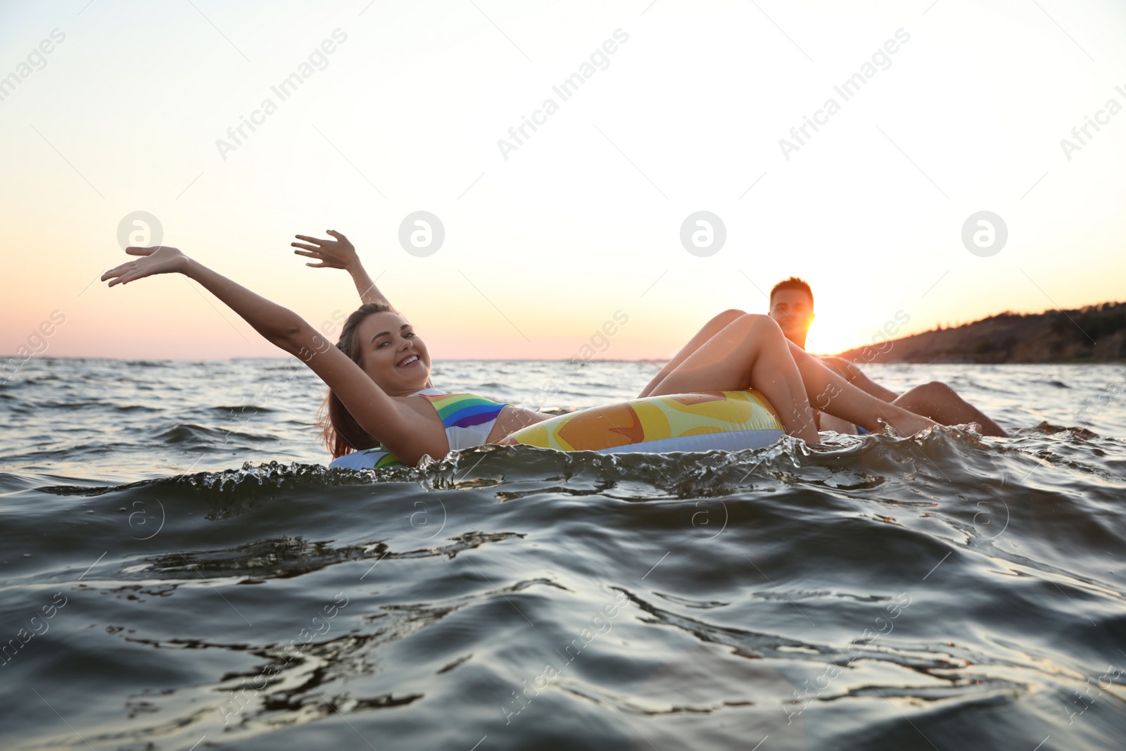 Photo of Happy young couple on inflatable rings in water