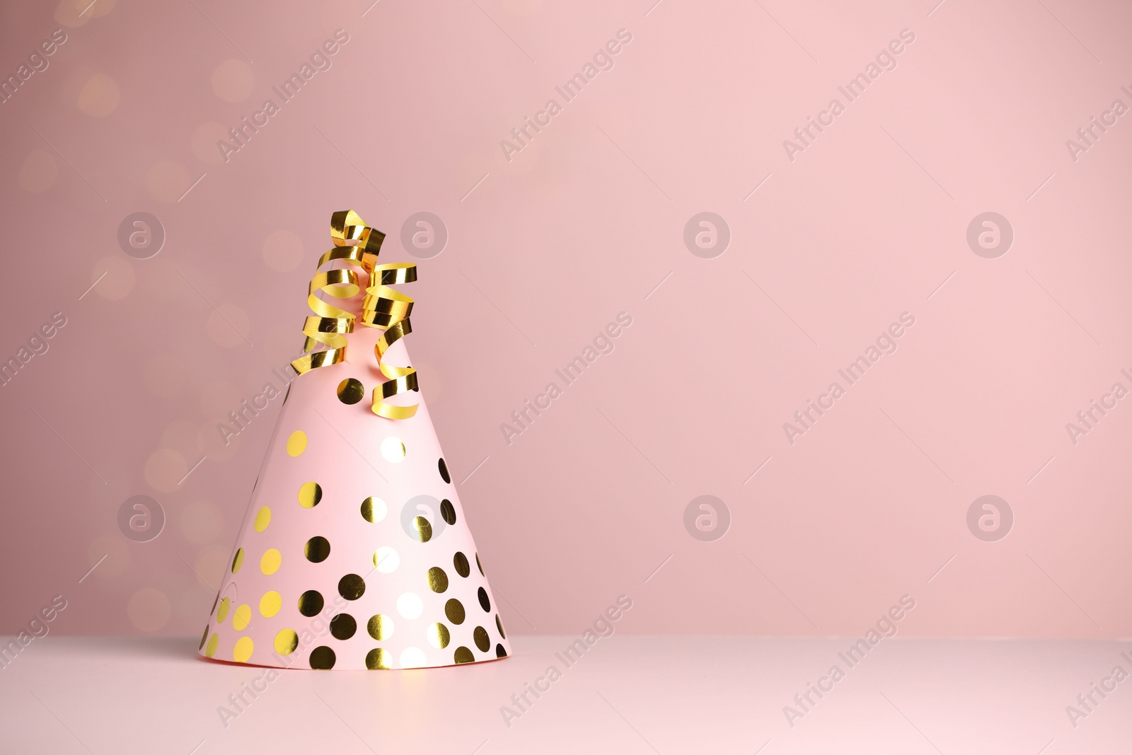 Photo of Party hat and serpentine streamers on dusty pink background, space for text