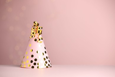 Photo of Party hat and serpentine streamers on dusty pink background, space for text